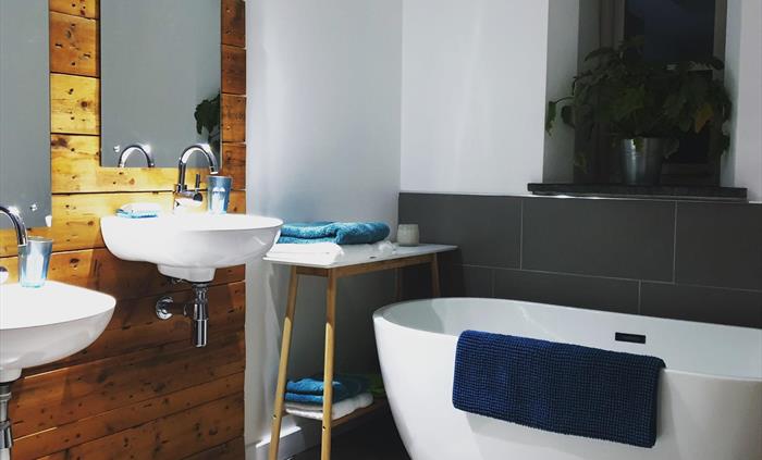 Accessible bathroom with high and low twin sinks, walk-in rainfall shower and freestanding bath tub.